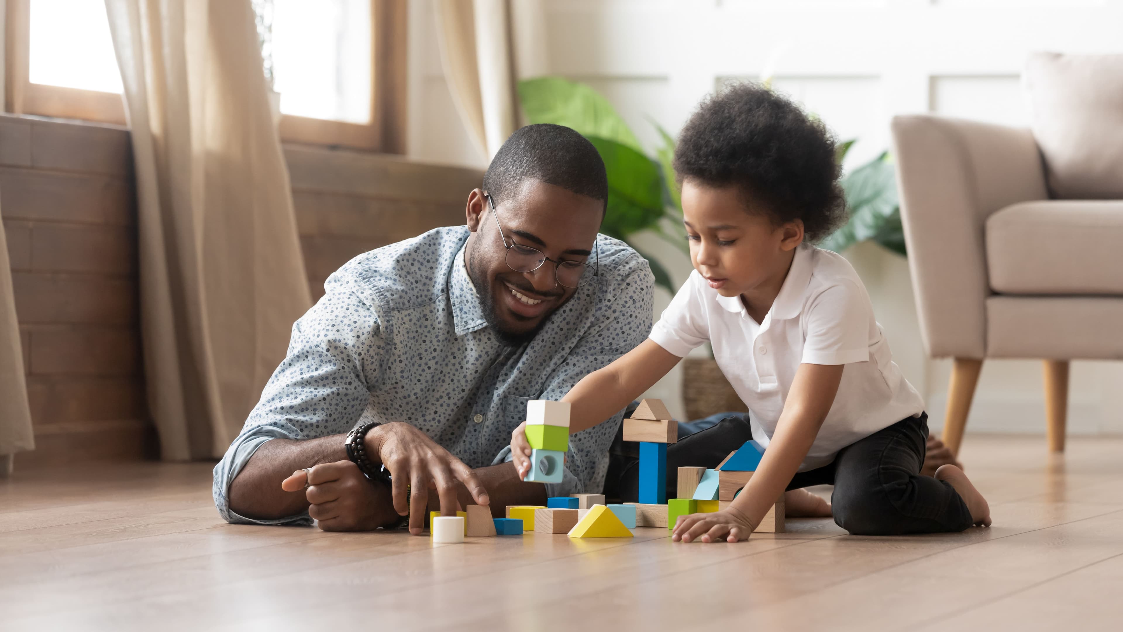 Father and son playing with toy blocks on the floor